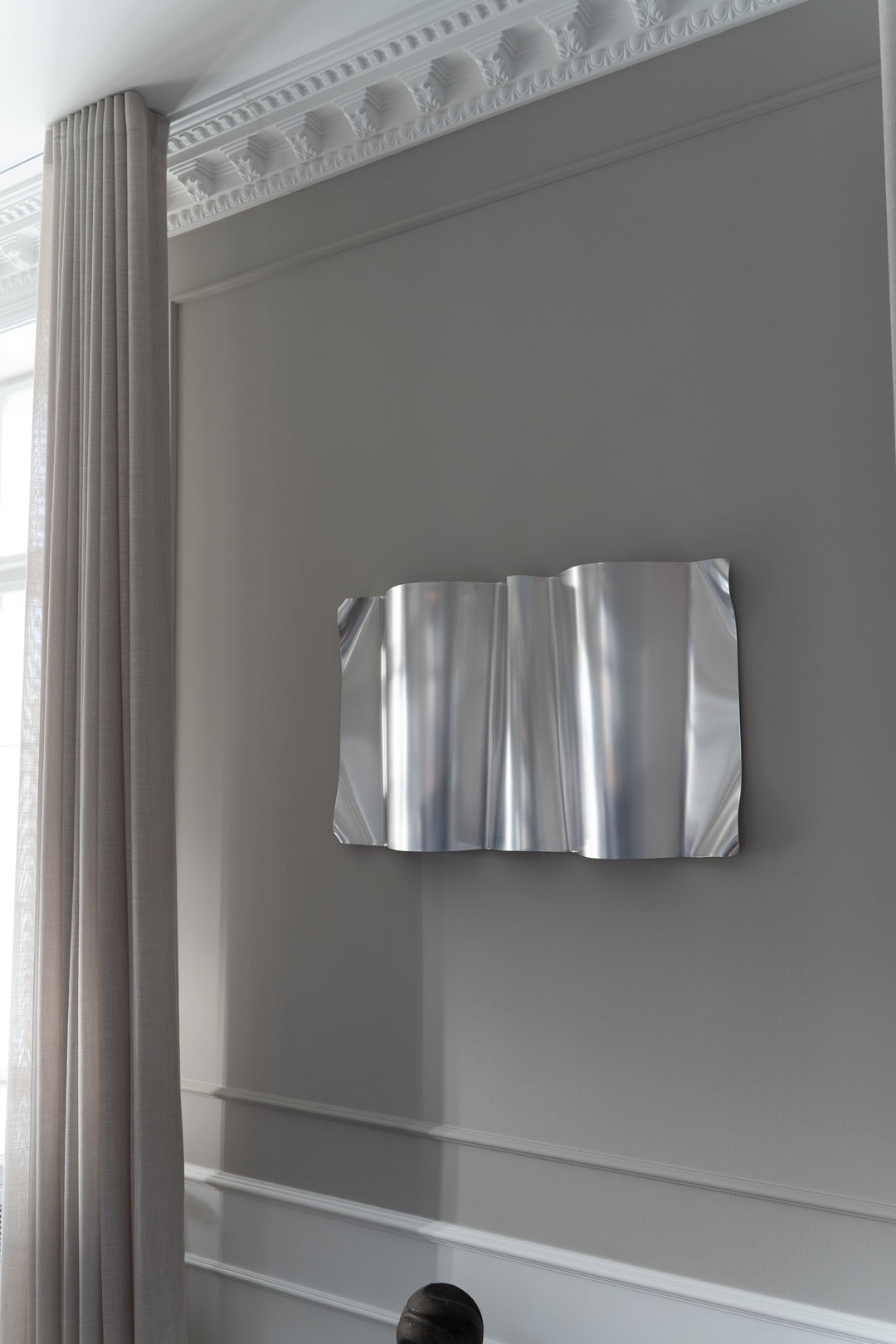 Silver abstract wall art on a gray wall