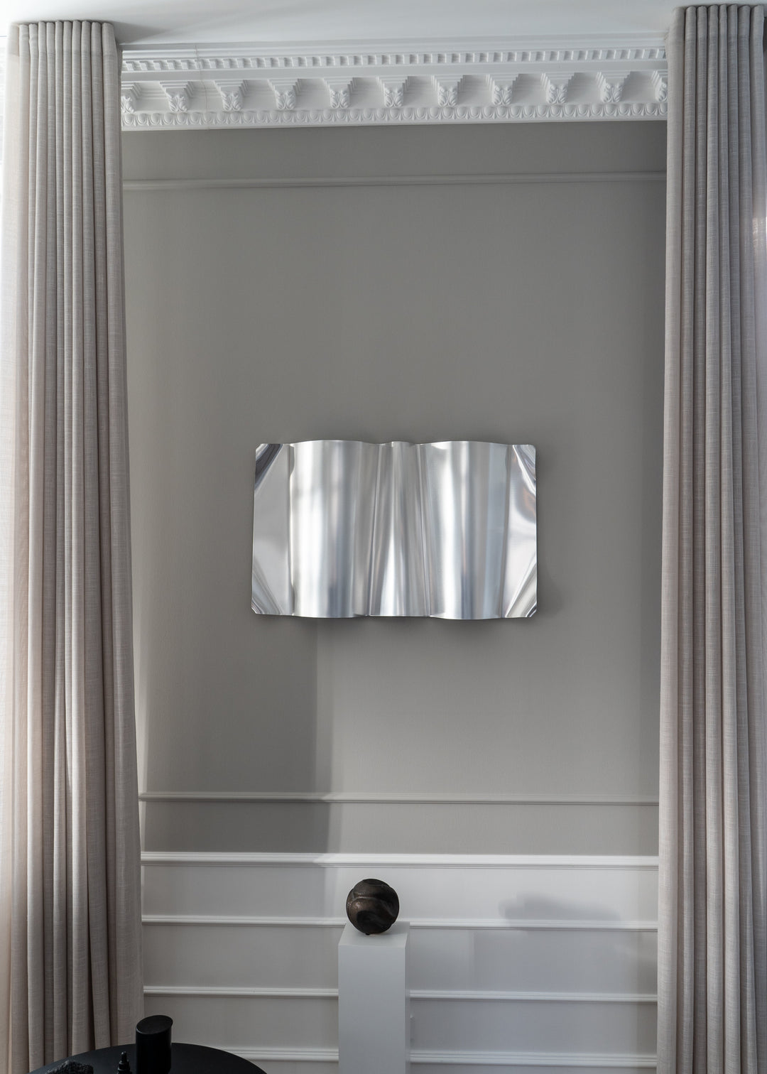 Silver Wavy Metal Art  from Juul studio on a a wall with curtains.